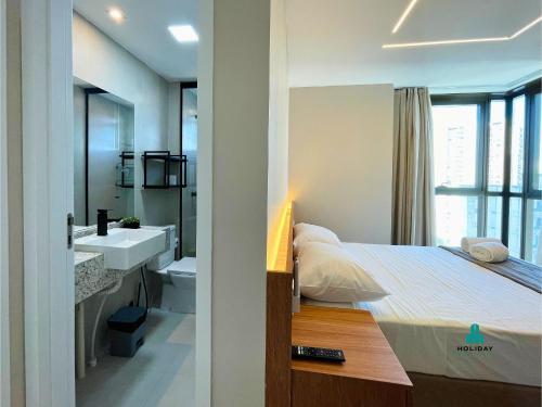 ein Schlafzimmer mit einem Bett und ein Badezimmer mit einem Waschbecken in der Unterkunft Beach Class Meireles by Holiday Stays in Fortaleza