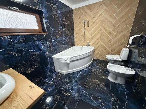 ein Badezimmer mit Badewanne, Toilette und Waschbecken in der Unterkunft Pensiunea Seraris in Voineasa