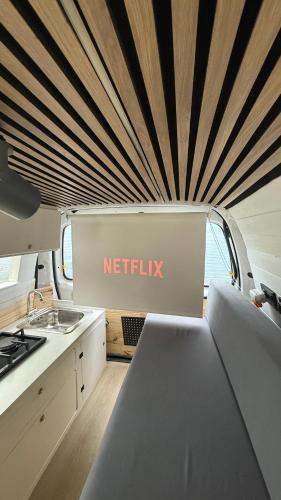 a kitchen in an rv with a netflix sign on the wall at Mini Camper Van Hot Water, You Can Drive it in Telde
