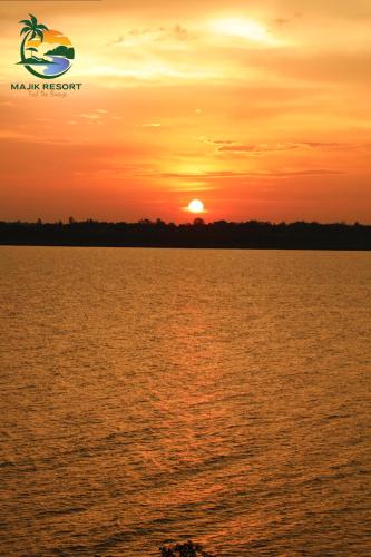 Una puesta de sol sobre el agua con la puesta del sol en Majik Resort Beach, en Busia