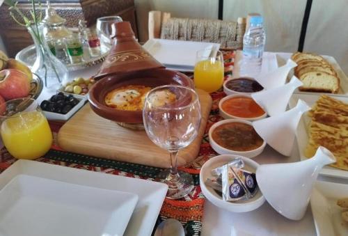 ein Tisch mit Essen und einem Glas Wein in der Unterkunft Sandrock Luxury Camp in Merzouga