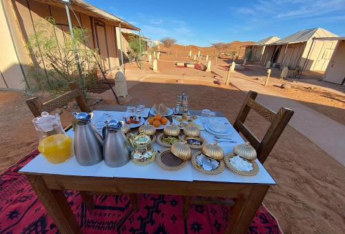 einen Tisch mit Küchenutensilien und Teller mit Essen drauf in der Unterkunft Sandrock Luxury Camp in Merzouga