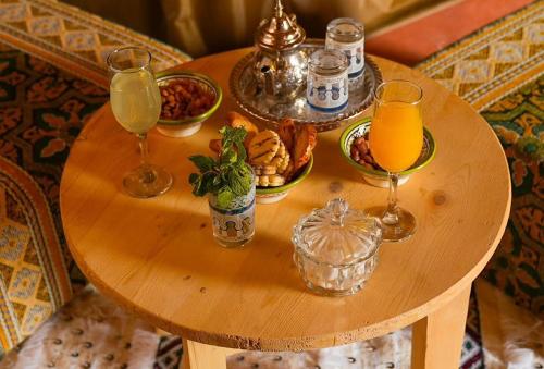 ein kleiner Holztisch mit Getränken und Speisen darauf in der Unterkunft Sandrock Luxury Camp in Merzouga