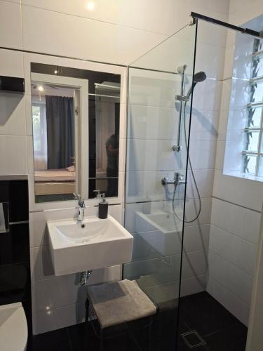 a white bathroom with a sink and a shower at Komfort Noclegi in Blizne Łaszczyńskiego