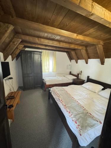 two beds in a room with wooden ceilings at Ski Rostovo - Hotel Rostovo & Ethno Village in Čardaci