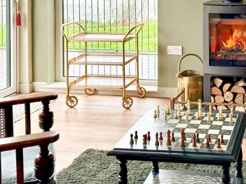 een schaakspel op een tafel in een woonkamer met open haard bij Talltrees - Uk42842 in Uplowman