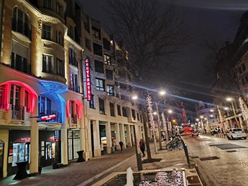 a city street at night with buildings and lights at Hôtel Cecyl Reims Centre in Reims