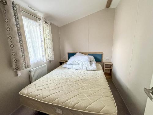 内兹岬附近沃尔顿Lovely 8 Berth Caravan With Decking To Hire At Naze Marine In Essex Ref 17030Ga的一间带床的卧室，位于一间有窗户的房间里