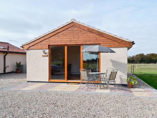 a patio with a table and an umbrella at Hawthorne Cottage in Winthorpe