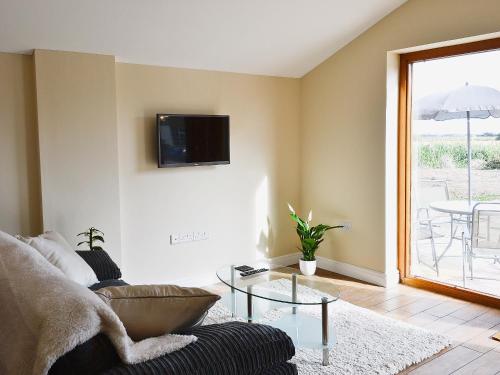a living room with a couch and a tv on the wall at Hawthorne Cottage in Winthorpe