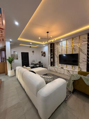 a living room with white furniture and a flat screen tv at Quantum Havens Apartment - LISBON in Akure
