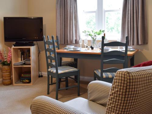 een woonkamer met een tafel met stoelen en een televisie bij Elm Court 7 in Keswick