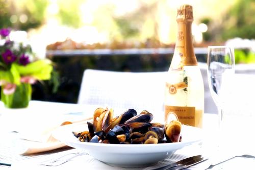 a bowl of mussels on a table with a bottle of champagne at Primoretz Grand Hotel & Spa in Burgas City