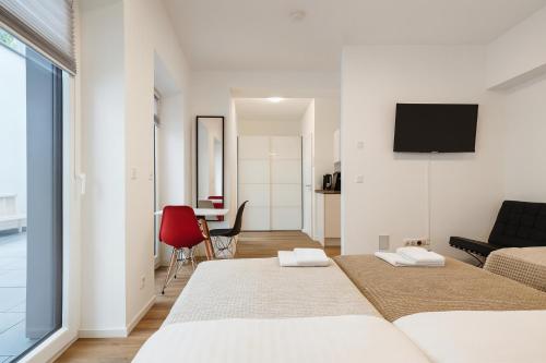 a white bedroom with two beds and a red chair at Old Town Apartments in Düsseldorf