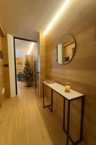 a hallway with a table and a mirror and a christmas tree at Chalet Campiglio Mountain View - Guardabassi Collection in Madonna di Campiglio
