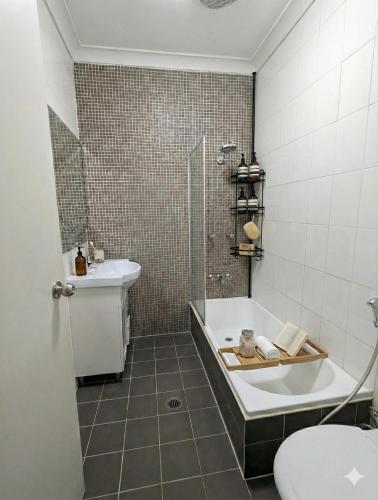 a bathroom with a tub and a sink and a toilet at Huge 3Bed House and Backyard & 4 Car Park spaces and Near Parramatta in Wentworthville