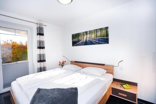 una camera da letto con un letto bianco e una finestra di Blankwasserweg 57, "Amina 2" a Grömnitzerhagen