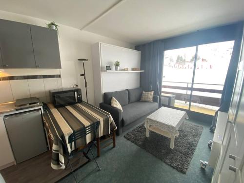 Una pequeña sala de estar con un sofá y una cocina. en Studio cosy pour 4 avec balcon et Wi-Fi, accès direct aux pistes - FR-1-602-59, en Arette
