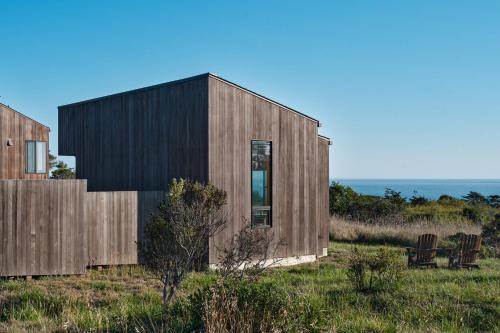 a wooden house with a black facade in a field at Wild Meadow in Sea Ranch