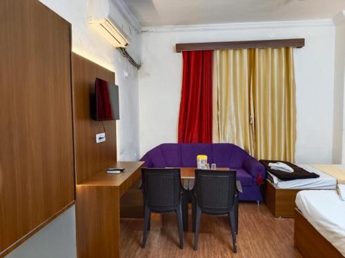a small room with a table and a purple couch at Hotel classic inn in Hyderabad