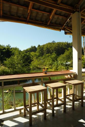 Eine Gruppe von Tischen und Hockern steht auf einer Veranda in der Unterkunft Eco Farm Stay and Hostel in Nongkhiaw