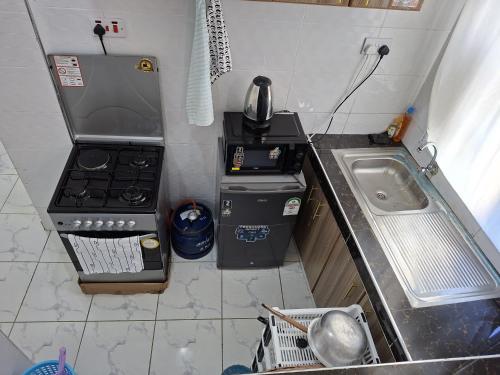 a small kitchen with a stove and a sink at cozy 1bedroom mombasa bamburi near the beach with hot shower, Netflix, Secured parking 07&07 for 95 then 61to18 in Mombasa