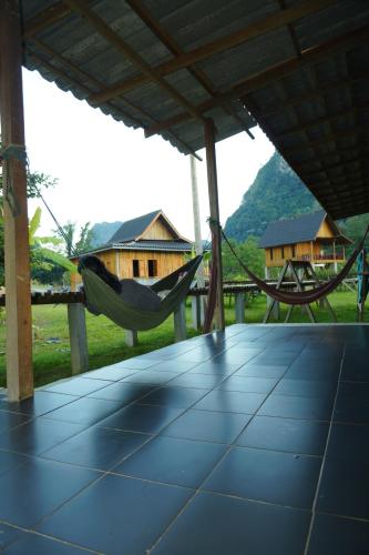 Eine Hängematte auf einer Veranda mit Häusern im Hintergrund in der Unterkunft Eco Farm Stay and Hostel in Nongkhiaw