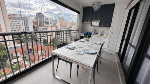 a white table and chairs in a room with a balcony at Apartamento Luxuoso 62 - São João in Sao Paulo