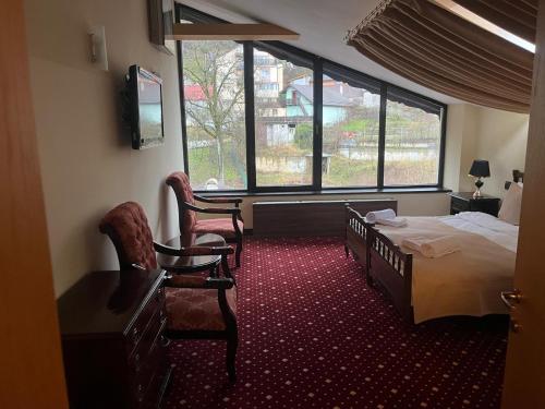 een slaapkamer met een bed en twee stoelen en een raam bij Classic Inn Hotel by Radacini in Braşov
