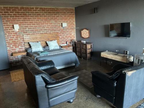 The Regiment Self Catering Accommodation has 3 x 4 sleeper units في Welgemoed: غرفة نوم بسرير وكرسيين جلديين