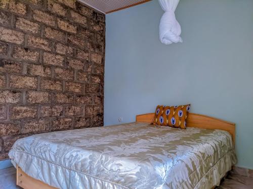 a bed in a room with a brick wall at Romanesca Motel in Rubavu