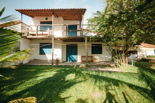 una casa bianca con un balcone e un cortile di Pura Vida Hostel e Pousada - Boipeba a Ilha de Boipeba