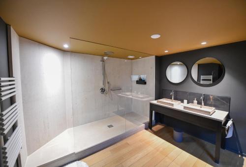 a bathroom with a shower and a sink and a mirror at Hôtel La SUITE & restaurant Le DÔME in Roanne