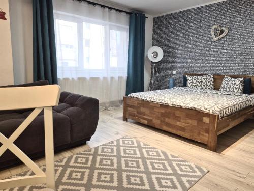 a bedroom with a bed and a couch and a window at Petrosani Central ApartHotel in Petroşani
