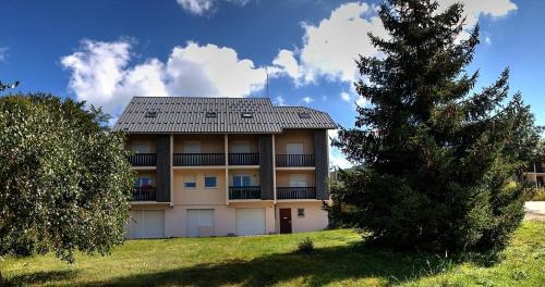 勒格兰阿伯尔热芒L'échappée Belle的前面有一棵树的建筑物