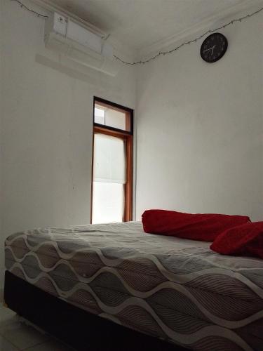 a bedroom with a bed and a clock on the wall at Homestay Tata in Bugisan