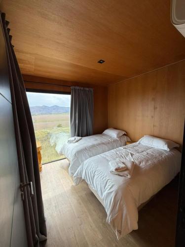 zwei Betten in einem Zimmer mit großem Fenster in der Unterkunft Finca Ocho Cerros in Tornquist