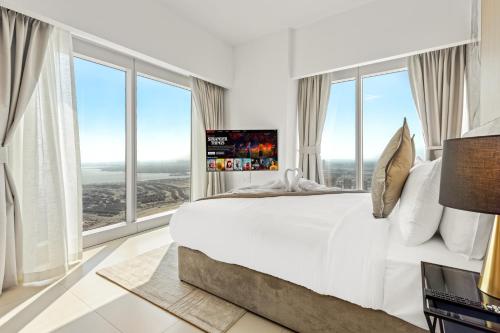 a bedroom with a large white bed with large windows at Desert Key - Gate Tower Apartments in Abu Dhabi