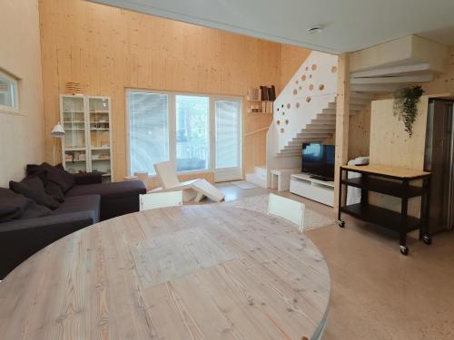 a living room with a wooden table and a staircase at The other side of the CLT semi-detached house, with a separate SPA in Lahti