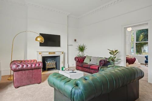 a living room with red leather furniture and a fireplace at The Regents Park Townhouse in London