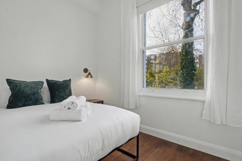 a white bed in a room with a window at The Regents Park Townhouse in London