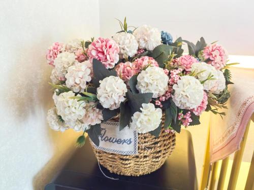 青岛青岛旺莎主题民宿的桌子上放着一个装满粉色和白色花朵的篮子