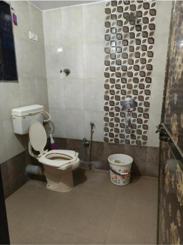 a bathroom with a toilet and a bucket in it at Divyesh Holiday Home in Nagaon