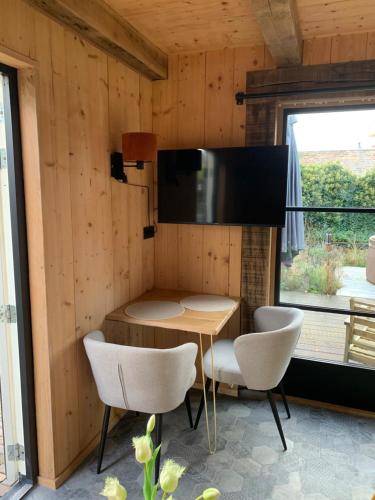 ein Esszimmer mit Tisch und Stühlen und einem Fernseher in der Unterkunft Onder de Oude Walnoot in Sint Pancras