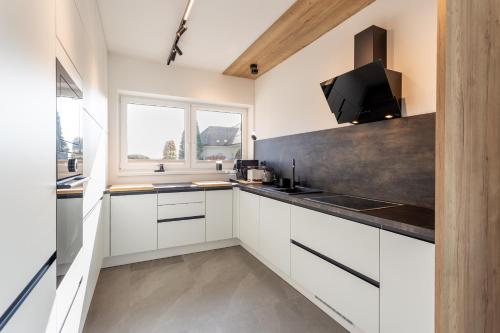 a kitchen with white cabinets and a large window at Hiša Urma in Celje