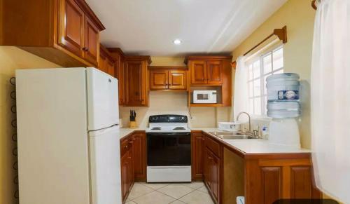 Una cocina con gabinetes de madera y un refrigerador blanco. en Paradise suites &residence, en San Pedro