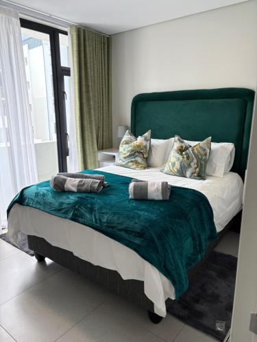 a bedroom with a large bed with a green headboard at Flat 4 Block 12 Bellamare in Port Elizabeth