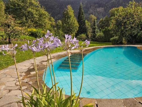 una piscina blu con fiori viola accanto di Kreithner luxury apartments a Vandoies