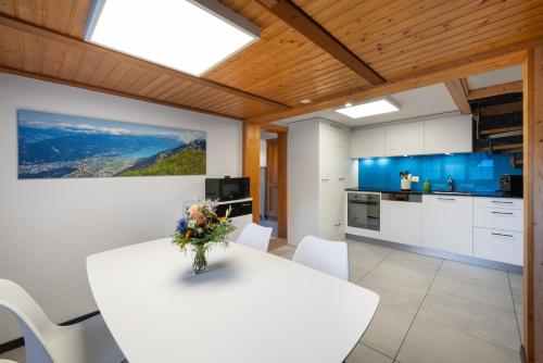 Una cocina y un comedor con una mesa y sillas blancas. en Apartment Steini since 1574, en Wilderswil
