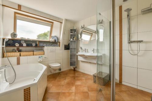 Un baño con bañera, lavabo y ducha. en B&B De Duinhoek, en Beverwijk